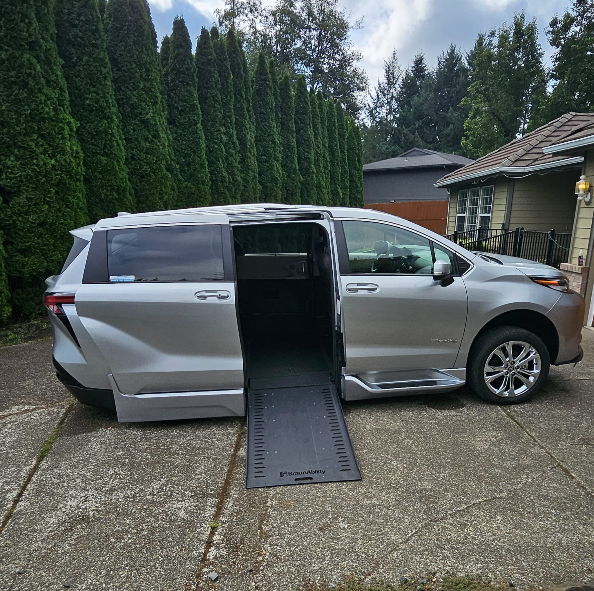 Bellandy’s silver wheelchair-accessible van with its side door open and ramp deployed